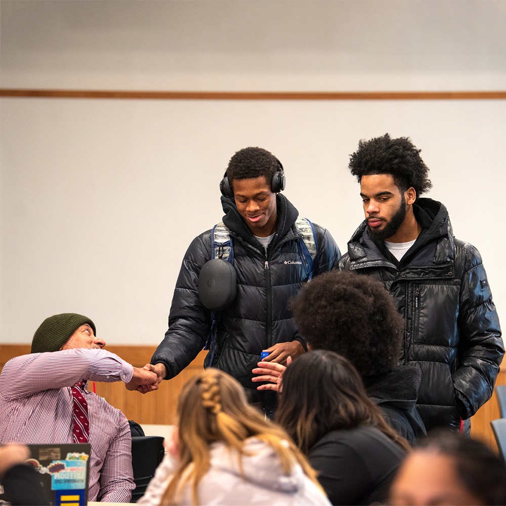students shaking hands with a professor during a meet and greet lunch event at the college