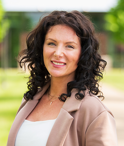 woman with dark hair in tan coat smiling